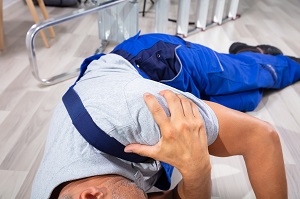 man laying on the ground holding his shoulder